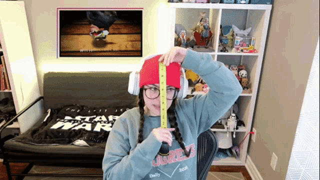a woman wearing a star wars sweatshirt measures her hat