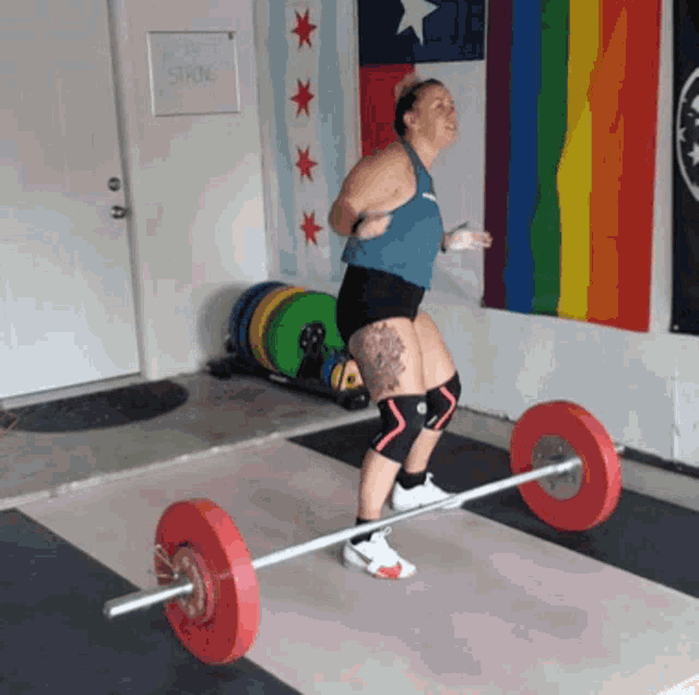 a woman is lifting a barbell in front of a sign that says " work strong "