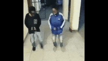a man and a woman are walking down a hallway in a building .