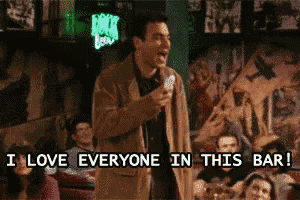 a man singing into a microphone in a bar with the words " i love everyone in this bar " below him