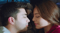 a man and a woman are kissing each other in bed .