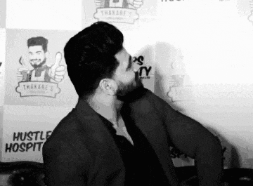 a black and white photo of a man with a beard giving a thumbs up sign .