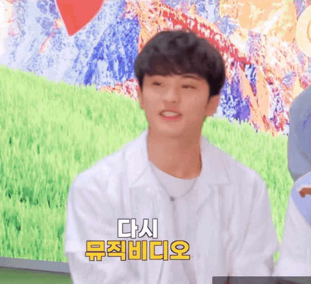 a man in a white jacket is dancing in front of a colorful background with foreign writing