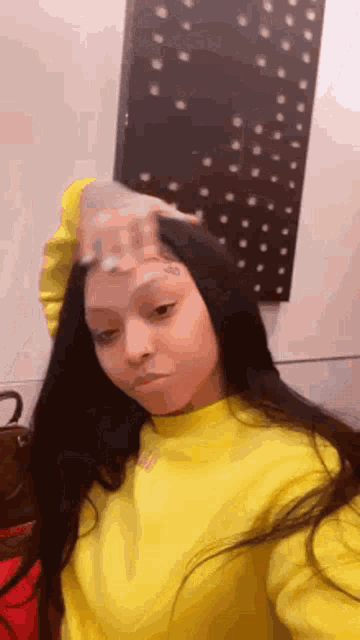 a woman wearing a yellow sweater is taking a selfie .
