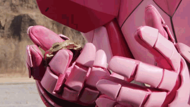 a close up of a pink robot holding a gold object
