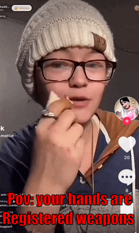 a woman wearing glasses and a beanie eating a sandwich with the caption prov your hands are registered weapons above her