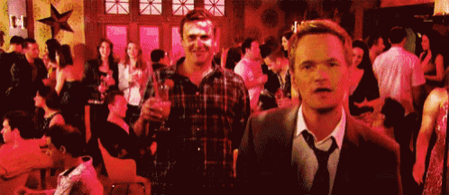 two men are standing in a crowded room holding drinks