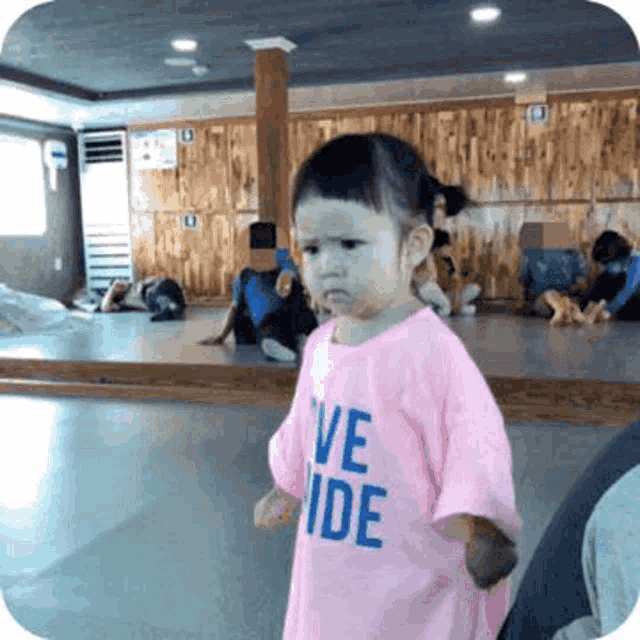 a little girl wearing a pink shirt that says " ve ide "