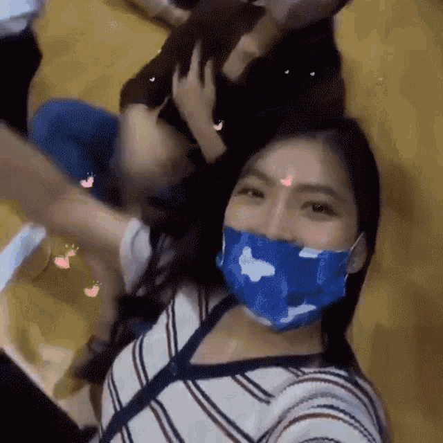 a woman wearing a blue face mask is taking a selfie with a group of people .