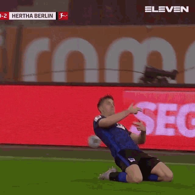 a soccer player celebrates a goal in front of a screen that says hertha berlin