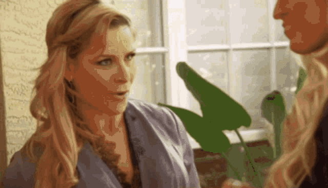 a woman with blonde hair is talking to another woman in front of a window