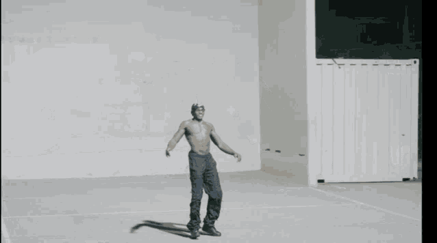 a man without a shirt is standing in front of a white wall with his arms outstretched