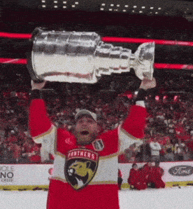 a man in a panthers jersey holds up a hockey trophy