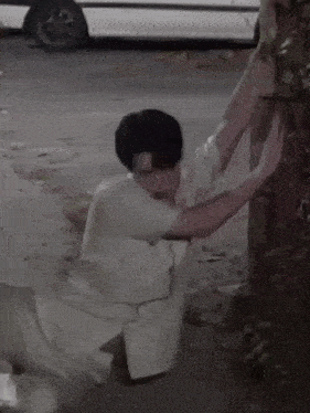 a man in a white shirt is kneeling down on the ground