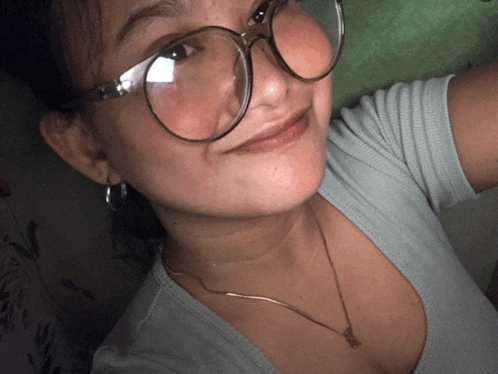a woman wearing glasses and a butterfly necklace smiles for the camera