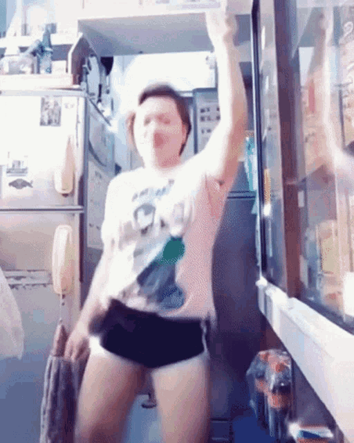 a woman is dancing in a kitchen wearing shorts and a shirt that says ' i am a pirate ' on it