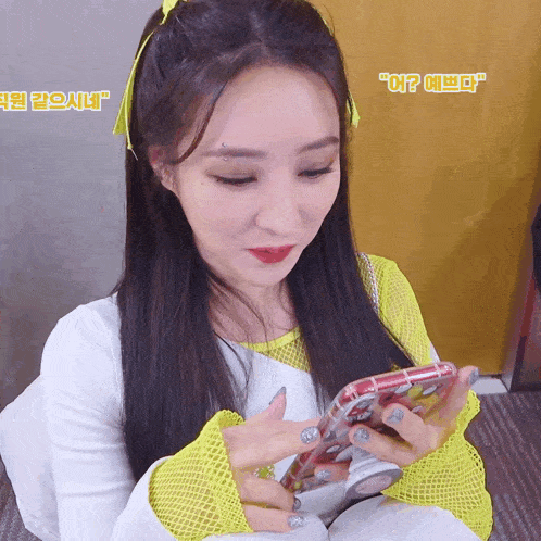 a woman in a yellow and white outfit is holding a cell phone in her hand