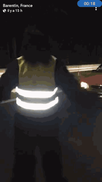 a phone screen shows a time of 20:20 and a person wearing a reflective vest