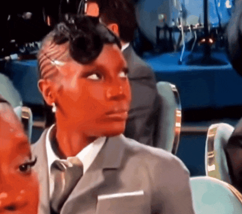 a woman wearing a suit and tie is looking at something