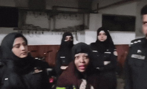a group of police officers are standing around a woman who is wearing a hijab