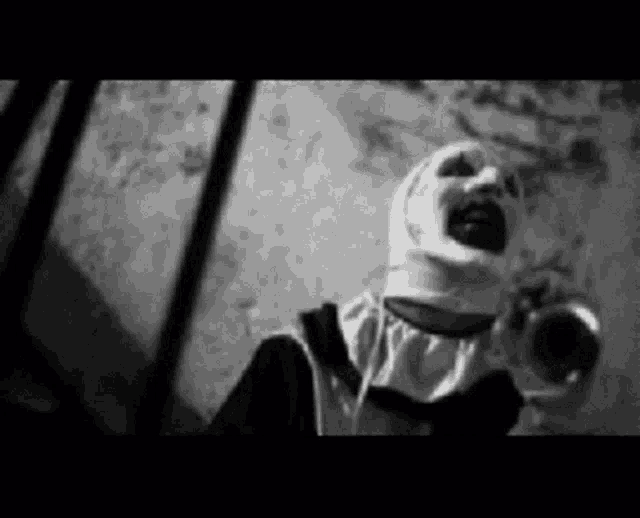 a black and white photo of a scary clown in a nun costume holding a trumpet .