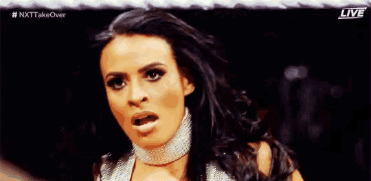 a woman is wearing a choker and making a funny face while standing in front of a crowd .