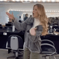 a woman is standing in a salon with her arms outstretched and a chair in the background .