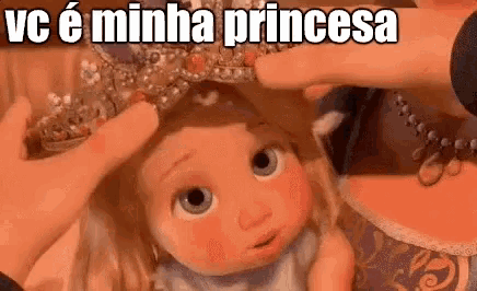 a person is putting a crown on the head of a baby doll .