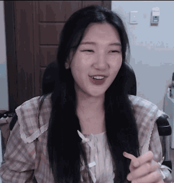 a woman with long black hair is sitting in a chair smiling