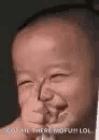 a baby is making a funny face while holding a glass .