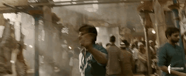 a man in a crowded area with a red chillies logo on the bottom right
