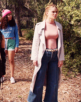 a girl wearing a blue alaska sweatshirt stands next to a woman in a trench coat