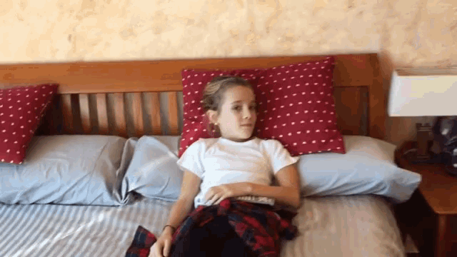a girl laying on a bed with a plaid shirt on