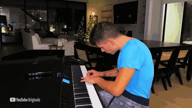 a man in a blue shirt is playing a piano with youtube originals written on the bottom