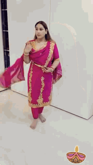 a woman in a pink and gold dress is standing in front of a white wall .