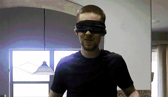 a man wearing a blindfold is standing in a kitchen