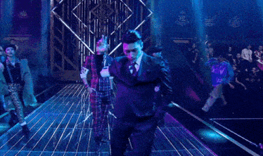a man in a suit and tie is dancing in front of a crowd wearing a new shirt