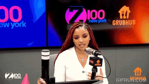 a woman is sitting in front of a microphone in front of a sign that says 100 new york