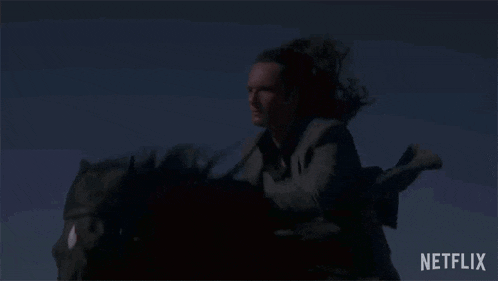 a man is riding a horse in the dark with a netflix logo behind him .