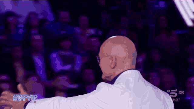 a bald man stands in front of a crowd with the hashtag #gfvip on his back
