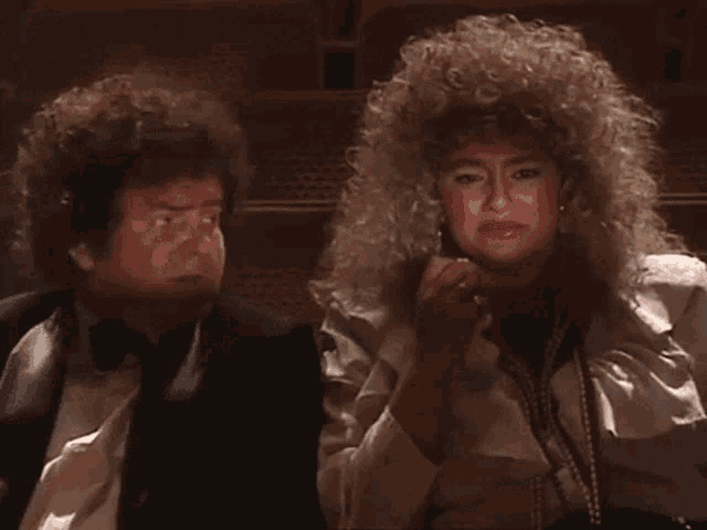 a man in a tuxedo and a woman with blonde curly hair are sitting next to each other