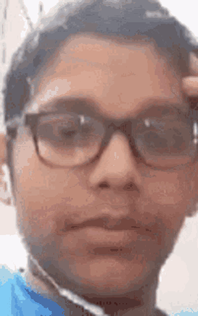 a young boy wearing glasses and ear buds is taking a selfie .