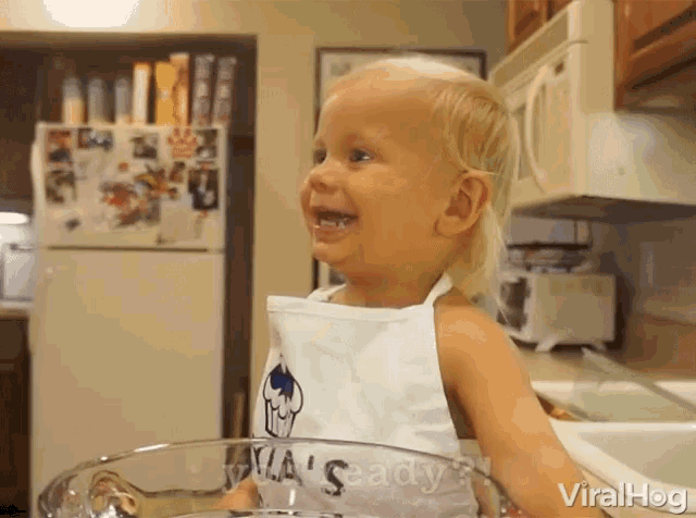 a little girl wearing an apron that says mia 's ready is standing in a kitchen