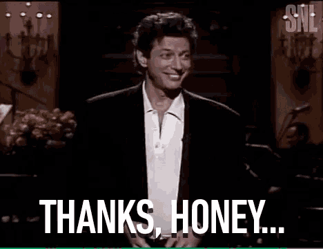a man in a suit and white shirt is standing in front of a microphone and saying thanks , honey .