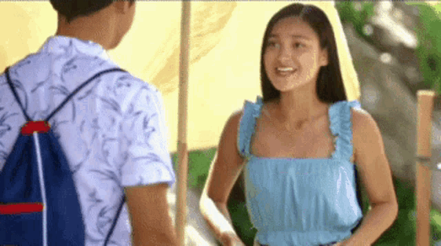 a man and a woman are standing next to each other and talking to each other .
