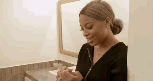 a woman is leaning against a wall in a bathroom while looking at her nails .