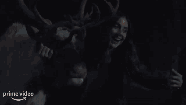 a woman is standing next to a reindeer that is wearing a christmas costume .
