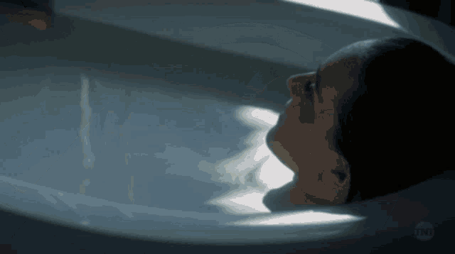 a woman is laying in a bathtub with the tnt logo visible
