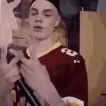a man in a red and yellow jersey is holding a gun in his hand .