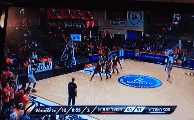 a basketball game is being played in a stadium with a hand tv logo on the floor